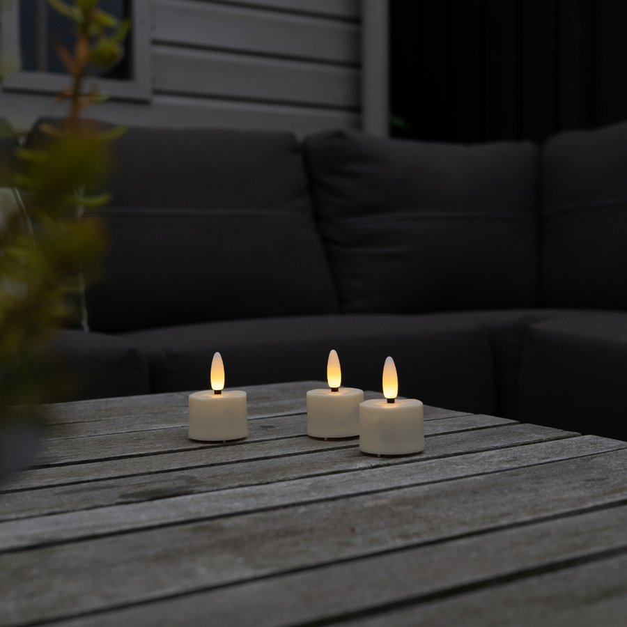 Drie Akaro waxinelichtjes op een houten tuintafel voor een loungebank