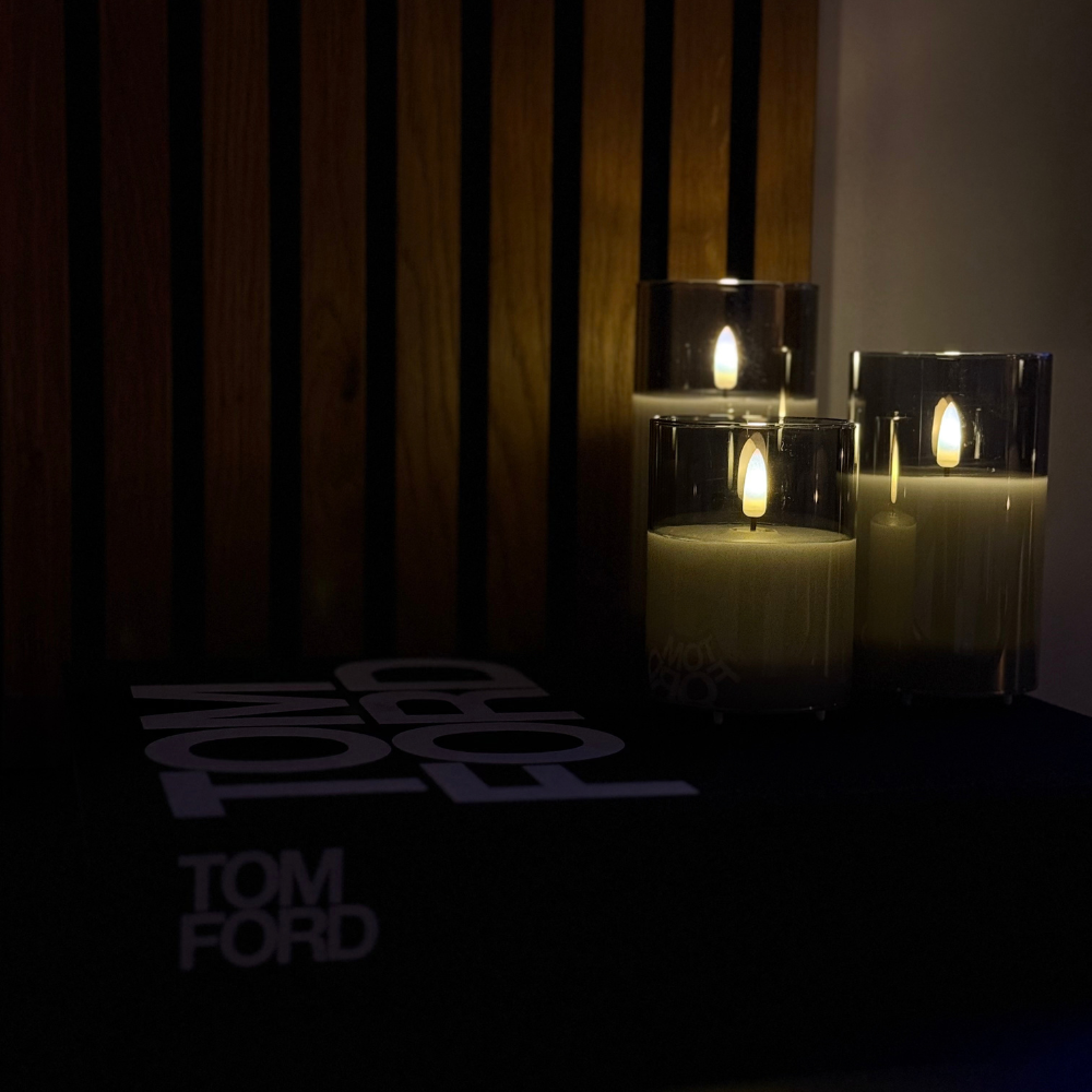 Drie Akaro kaarsen in glas op een donkere tafel voor een houten lamellenwand