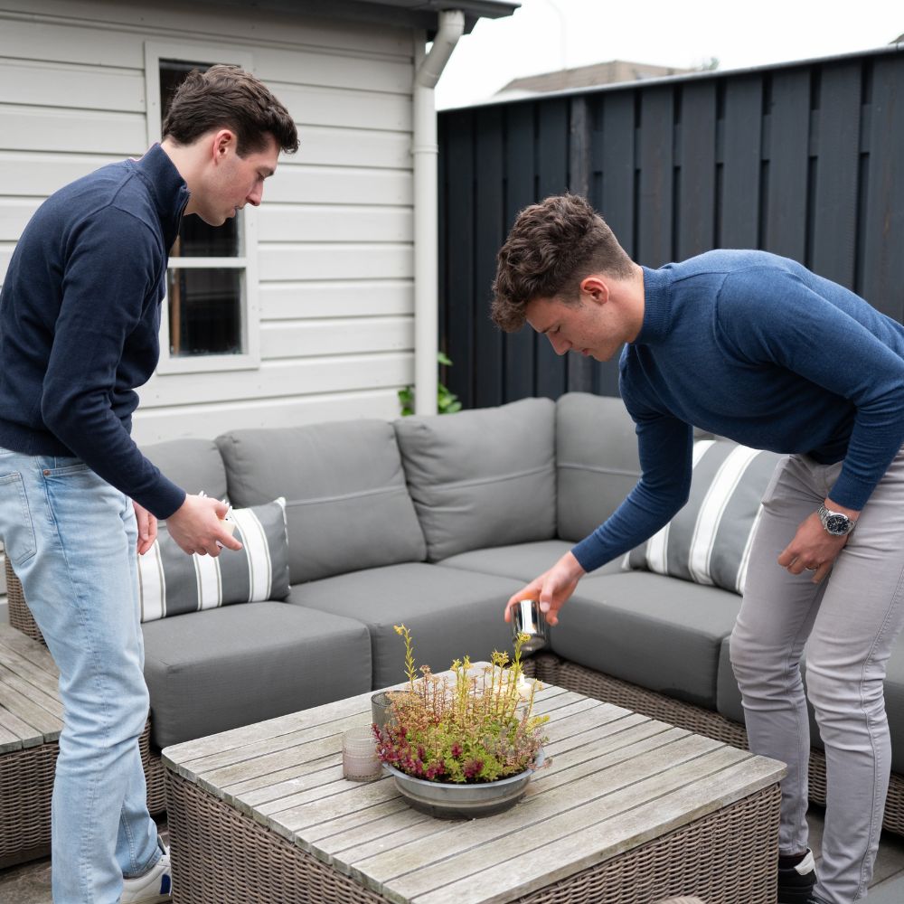 Tom en Floris zetten Akaro kaarsen neer op een tafel in een buitenlounge