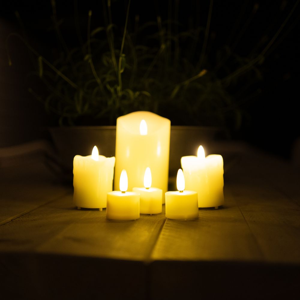 Zes brandende Akaro kaarsen en waxinelichtjes op een houten tafel
