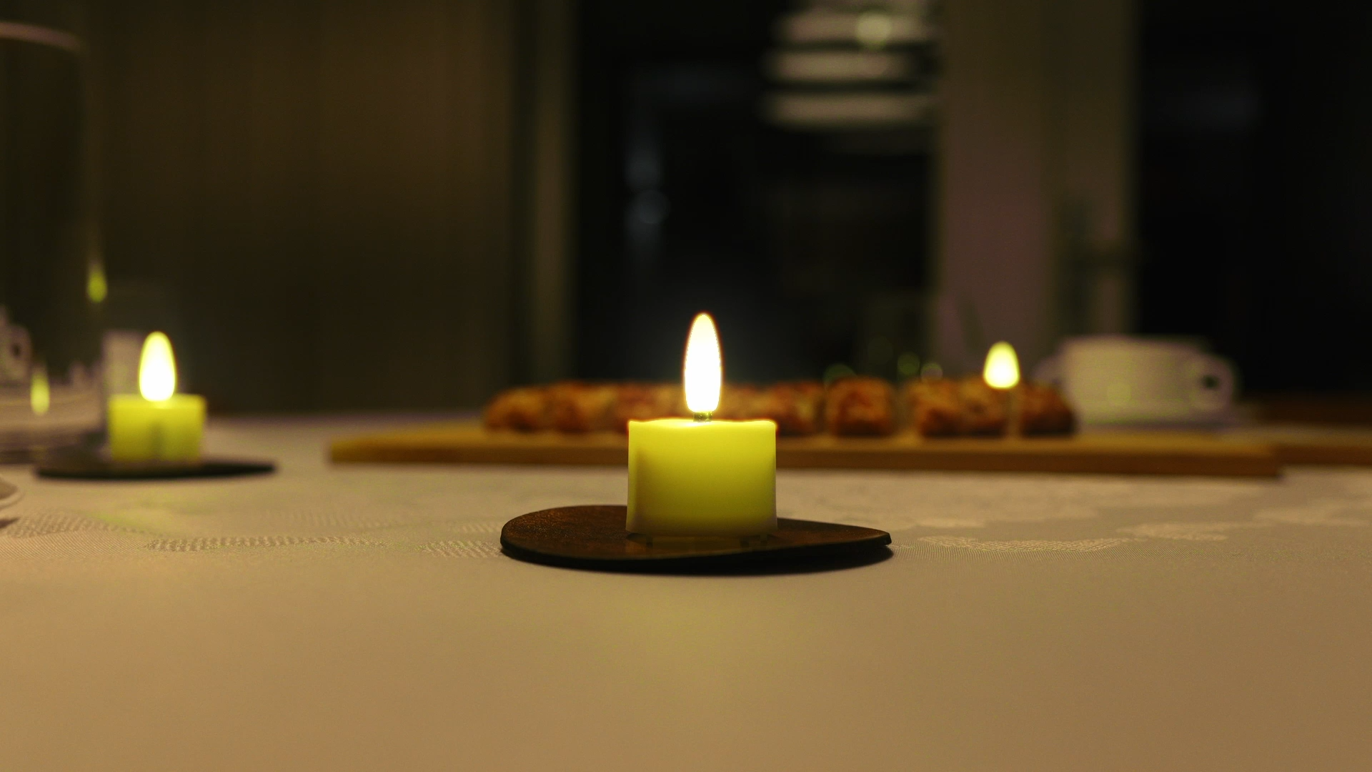 Ouder echtpaar op de bank in een donkere woonkamer, verlicht door een tafel vol Akaro waxinelichtjes